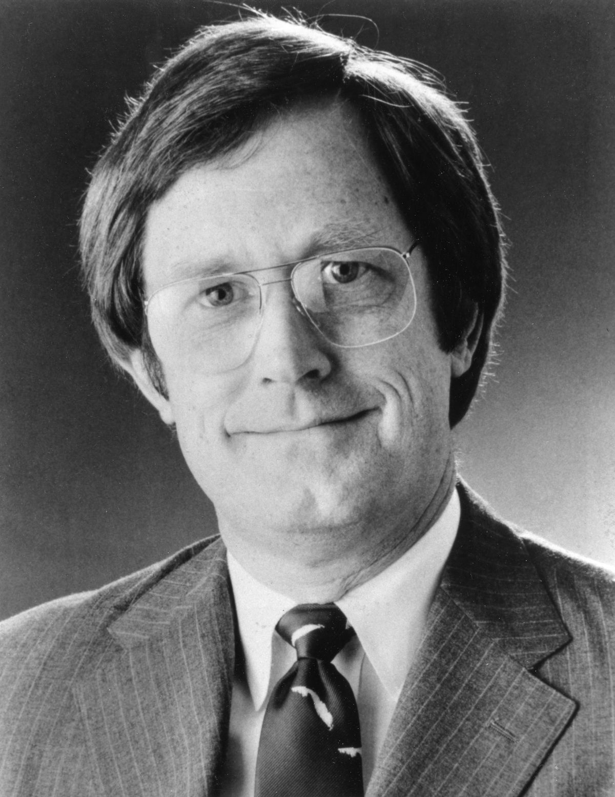 Black and white photo of William E. Sadowski. He is wearing glasses, a pinstripe suite jacket and tie with a closed mouth smile.